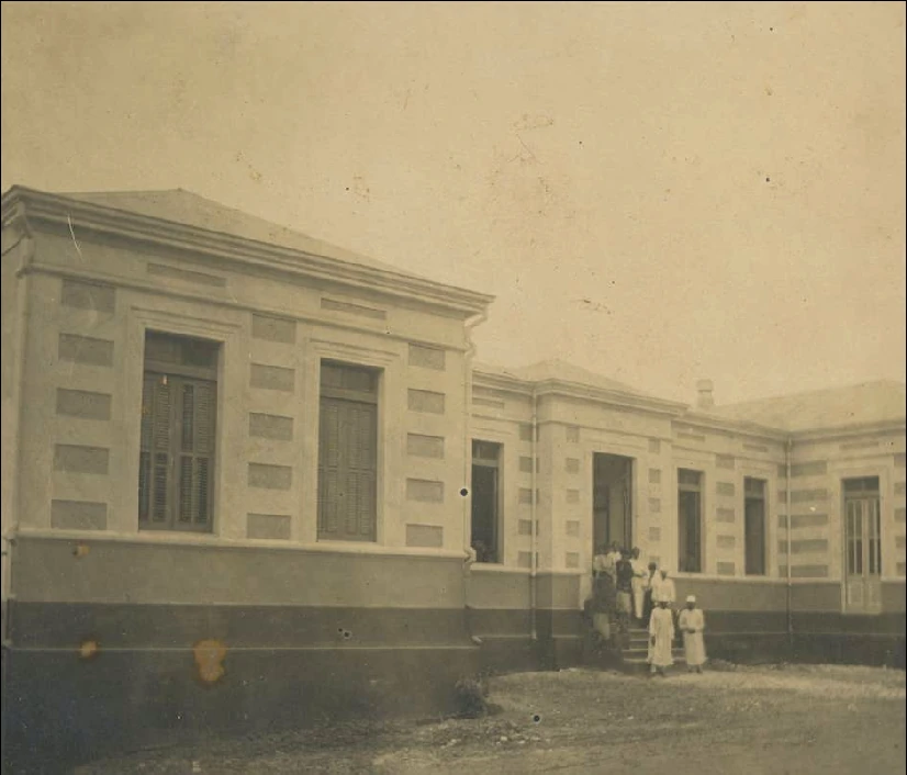 Historic municipal hospital building with several people near its entrance.